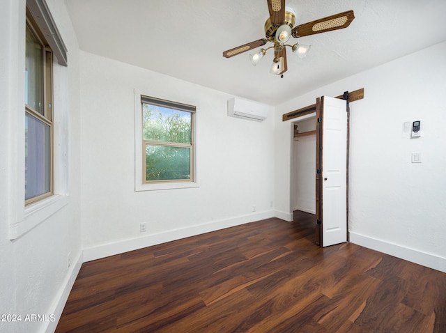 unfurnished bedroom with a closet, an AC wall unit, ceiling fan, and dark wood-type flooring