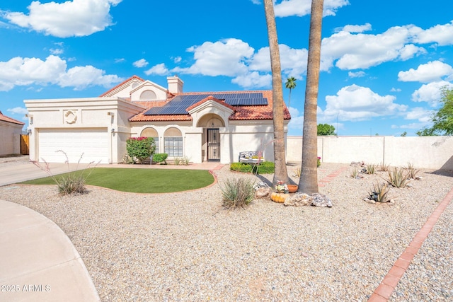 7503 W Julie Dr, Glendale, AZ 85308 - mediterranean / spanish house with a tiled roof, a garage, stucco siding, roof mounted solar panels, and concrete driveway