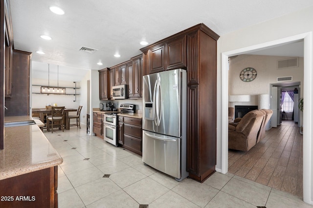 7503 W Julie Dr, Glendale, AZ 85308 - kitchen with stainless steel appliances, dark brown cabinets, a sink, recessed lighting, and a fireplace