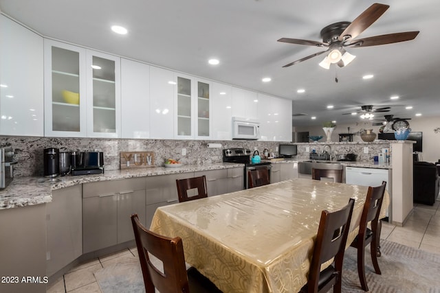 kitchen featuring tasteful backsplash, light stone counters, light tile floors, stainless steel electric stove, and white cabinetry