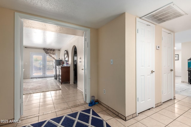 corridor featuring light tile floors and a textured ceiling