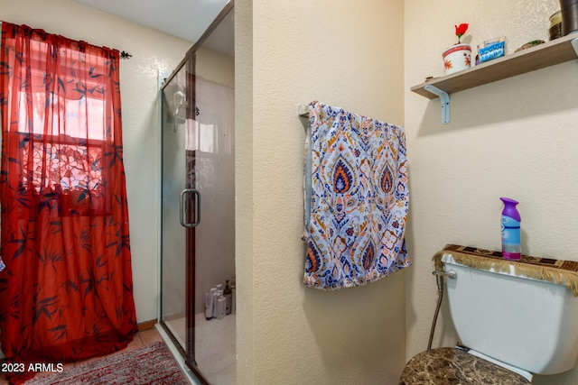 bathroom featuring tile flooring, a shower with door, and toilet