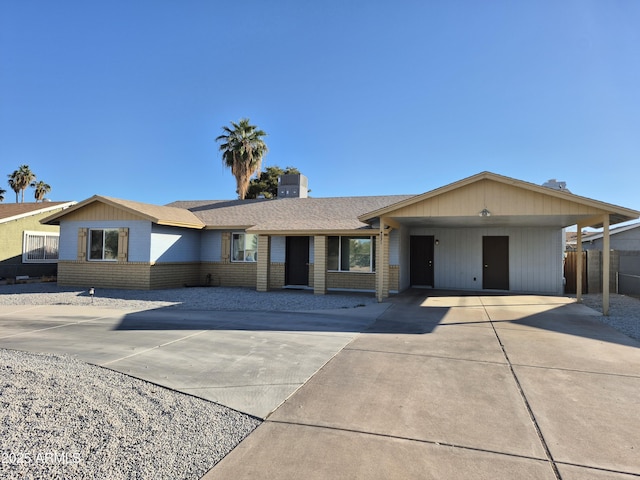 ranch-style house with driveway, a shingled roof, a carport, and brick siding