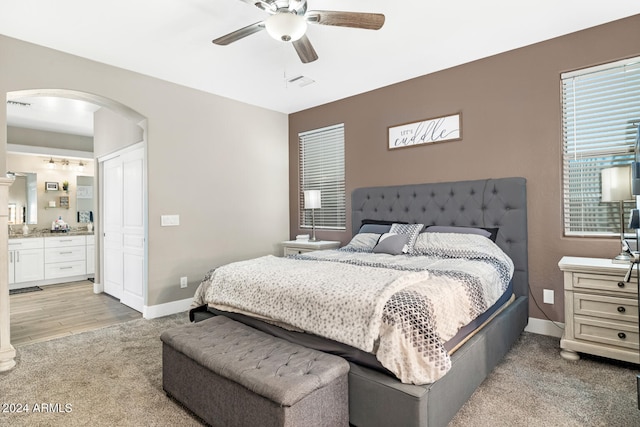 bedroom with ceiling fan, light hardwood / wood-style flooring, and connected bathroom