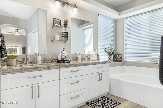 bathroom featuring hardwood / wood-style flooring, tiled bath, vanity, and plenty of natural light