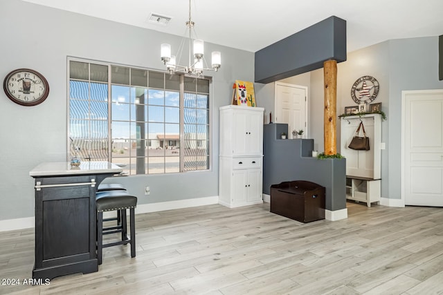 kitchen featuring pendant lighting, a notable chandelier, a kitchen breakfast bar, and light hardwood / wood-style floors