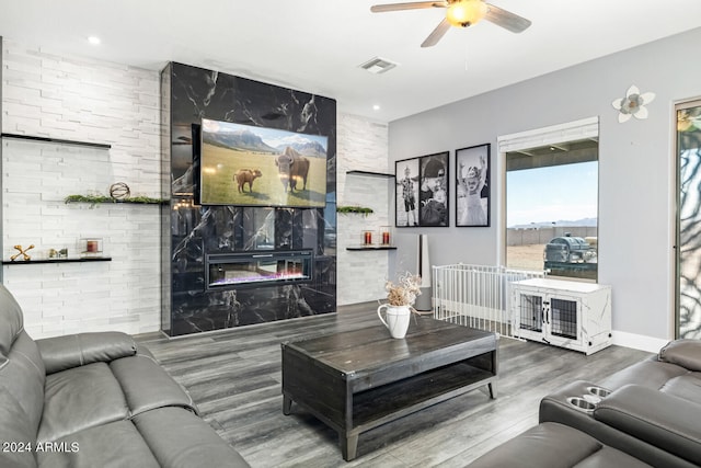 living room with a large fireplace, ceiling fan, and hardwood / wood-style floors