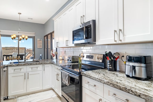 kitchen featuring white cabinetry, stainless steel appliances, an inviting chandelier, decorative light fixtures, and sink