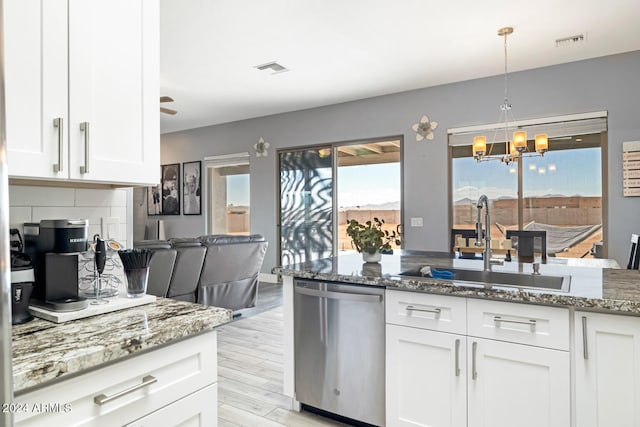 kitchen featuring light hardwood / wood-style floors, stainless steel dishwasher, white cabinetry, and pendant lighting