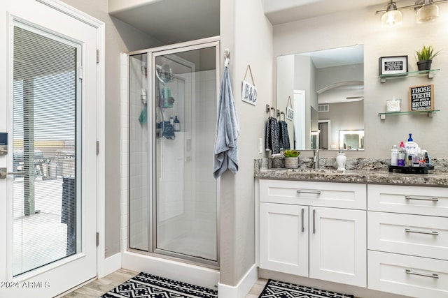 bathroom with a shower with door, hardwood / wood-style floors, and vanity