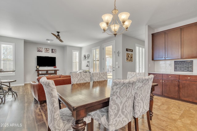 dining area featuring ceiling fan with notable chandelier, a wealth of natural light, and light wood-type flooring