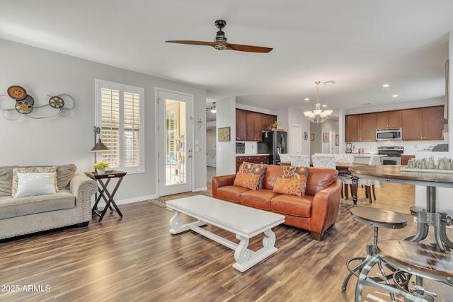 living room featuring dark hardwood / wood-style flooring and ceiling fan with notable chandelier