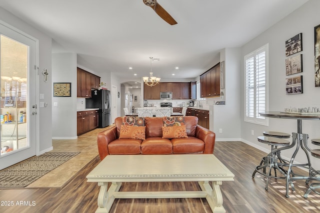 living room featuring hardwood / wood-style flooring, sink, and ceiling fan with notable chandelier