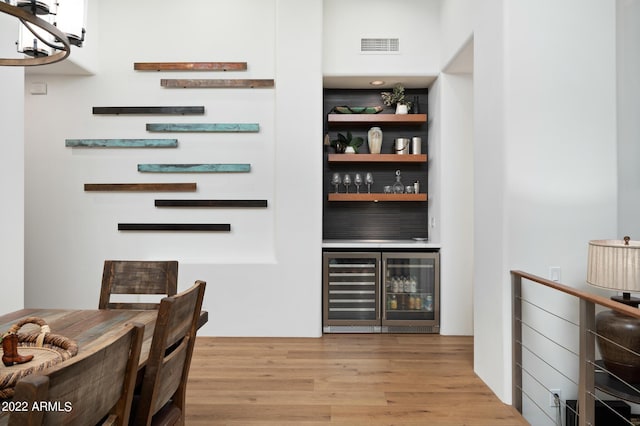 bar with beverage cooler and light wood-type flooring