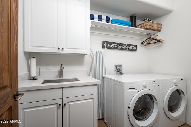 laundry room with sink, washing machine and dryer, and cabinets