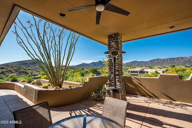 view of patio with ceiling fan, a mountain view, and a balcony