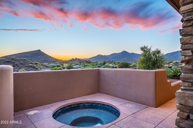 pool at dusk featuring an in ground hot tub and a mountain view