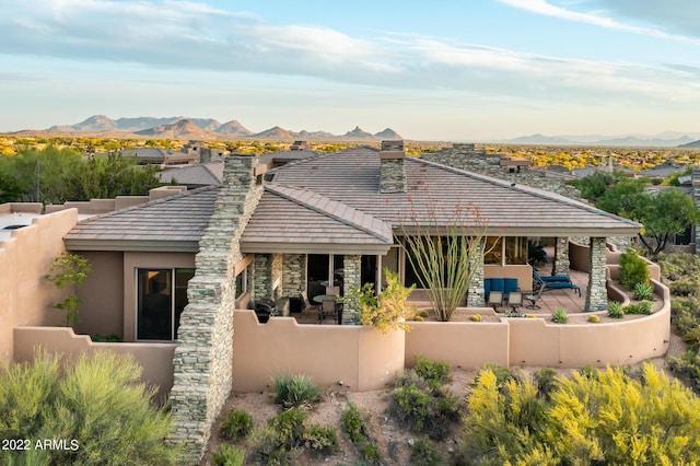 back of property featuring a patio, a mountain view, and an outdoor hangout area