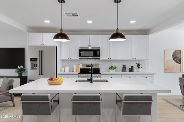 kitchen featuring white cabinets, sink, a kitchen island with sink, and appliances with stainless steel finishes