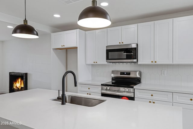 kitchen featuring white cabinets, sink, stainless steel appliances, and hanging light fixtures