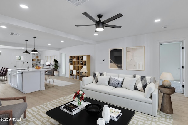 living room featuring ceiling fan, sink, and light wood-type flooring