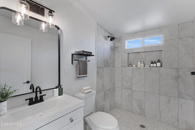 bathroom featuring tiled shower, vanity, and toilet