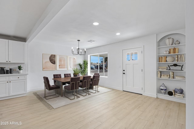 dining area featuring a chandelier, light hardwood / wood-style flooring, and built in features