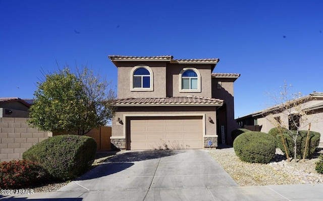19886 W Woodlands Ave, Buckeye, AZ 85326 - mediterranean / spanish house with concrete driveway, an attached garage, a tiled roof, stucco siding, and stone siding