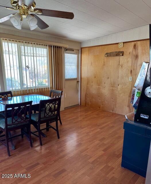 dining room featuring ceiling fan, hardwood / wood-style floors, and wood walls