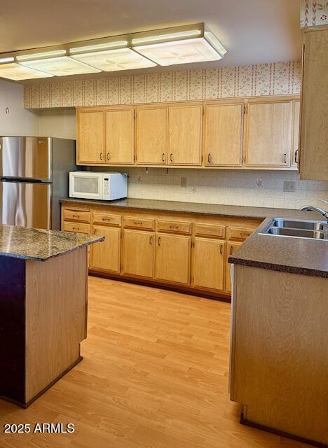 kitchen with sink, decorative backsplash, stainless steel fridge, and light wood-type flooring