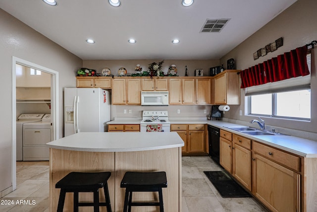 kitchen with a kitchen island, sink, a kitchen bar, washer and dryer, and white appliances