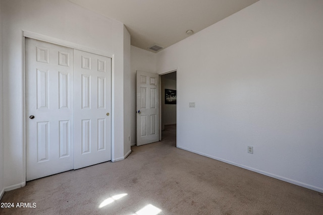 unfurnished bedroom with a closet and light colored carpet