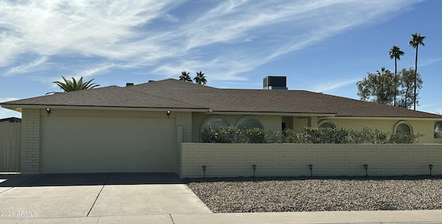 single story home with a garage, concrete driveway, a shingled roof, and fence