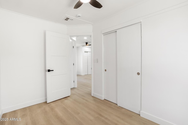 unfurnished bedroom with a closet, light hardwood / wood-style floors, ceiling fan, and crown molding