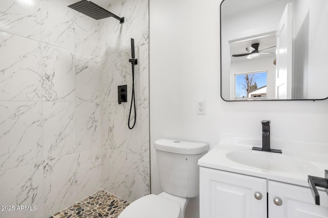 bathroom with a tile shower, vanity, toilet, and ceiling fan