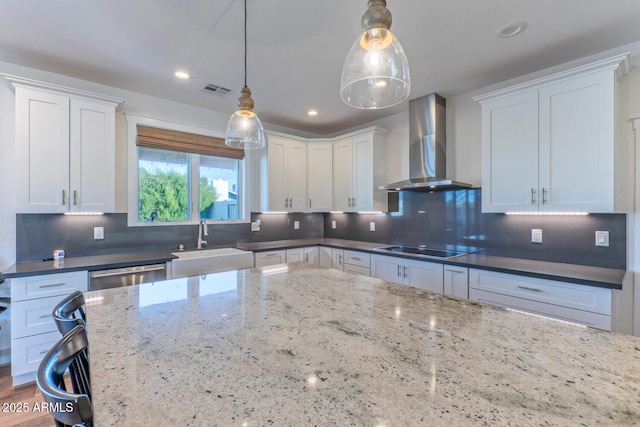 kitchen with hanging light fixtures, wall chimney range hood, white cabinets, and black electric cooktop