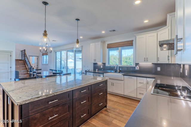 kitchen with sink, hanging light fixtures, a center island, white cabinets, and cooktop