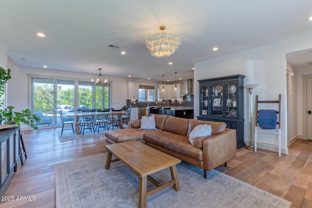 living room with an inviting chandelier and light wood-type flooring