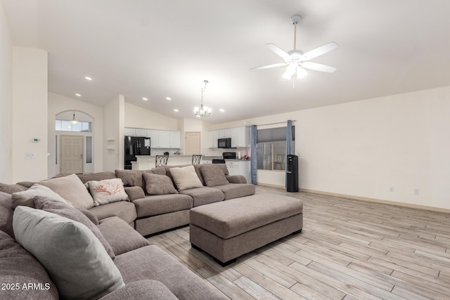 living room featuring ceiling fan with notable chandelier, light hardwood / wood-style flooring, and high vaulted ceiling