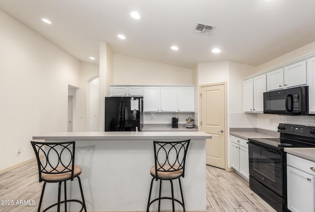 kitchen with white cabinetry, a center island, and black appliances