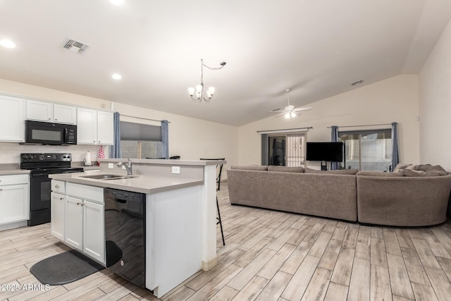 kitchen featuring sink, black appliances, hanging light fixtures, a kitchen island with sink, and white cabinets