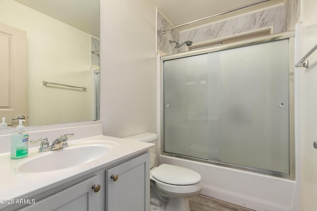 full bathroom with enclosed tub / shower combo, hardwood / wood-style floors, vanity, and toilet