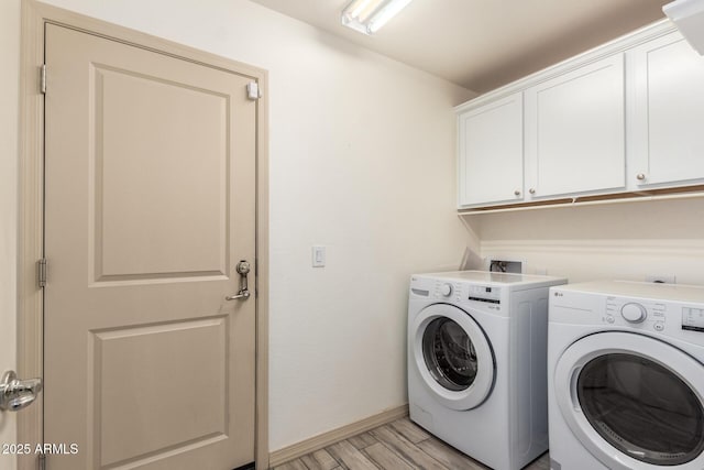 clothes washing area with cabinets, washer and clothes dryer, and light wood-type flooring