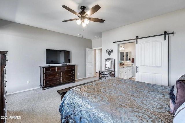 carpeted bedroom featuring ceiling fan, a barn door, and connected bathroom