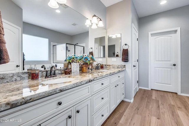 bathroom with hardwood / wood-style flooring, vanity, and a shower with shower door