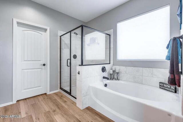 bathroom with wood-type flooring and shower with separate bathtub