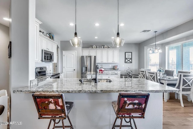 kitchen featuring kitchen peninsula, appliances with stainless steel finishes, decorative light fixtures, and white cabinets