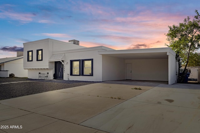 view of front of property featuring stucco siding, concrete driveway, and a carport