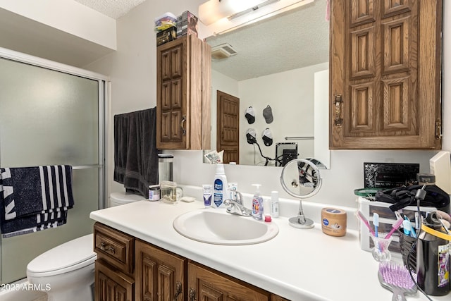 bathroom with visible vents, toilet, a stall shower, a textured ceiling, and vanity