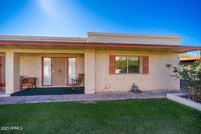 view of front of house with a patio area, a front lawn, and stucco siding